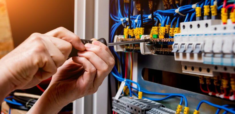 The man is repairing the switchboard voltage with automatic switches. Electrical background