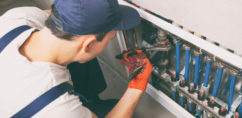 The man is repairing the heater system in the house